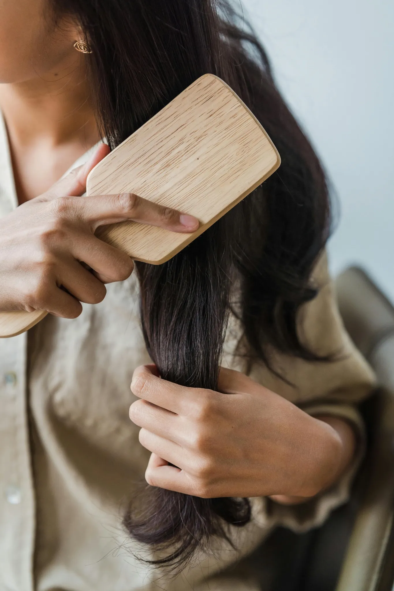 Woman grooming hair with wooden comb.