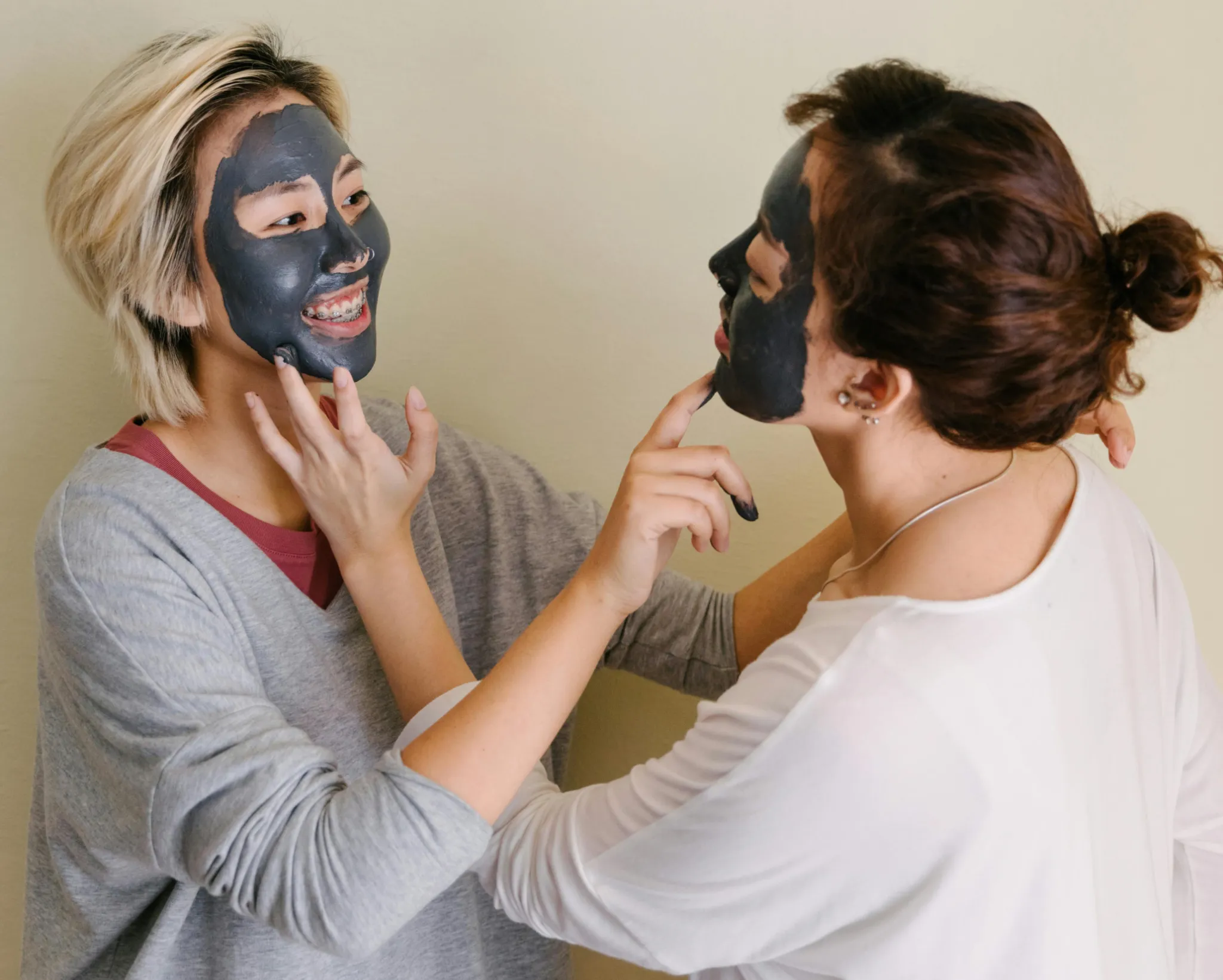 Girls applying facial clay masks for self-care. Home remedies for acne might help control it but erasing acne scars might require advanced treatments.